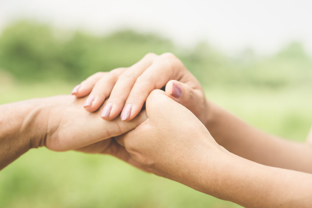 Two women holding hands in support of one another